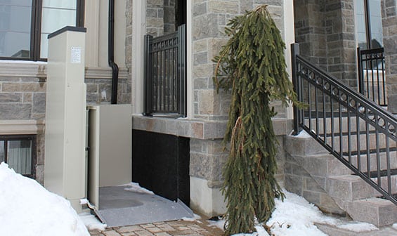 Outdoor Vertical Wheelchair Lift attached to stone patio