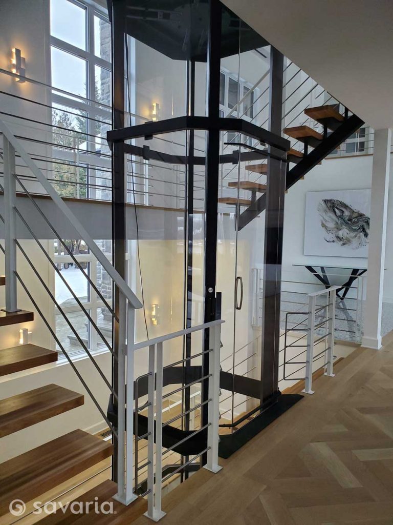 Octagonal glass elevator with black trim in luxury home