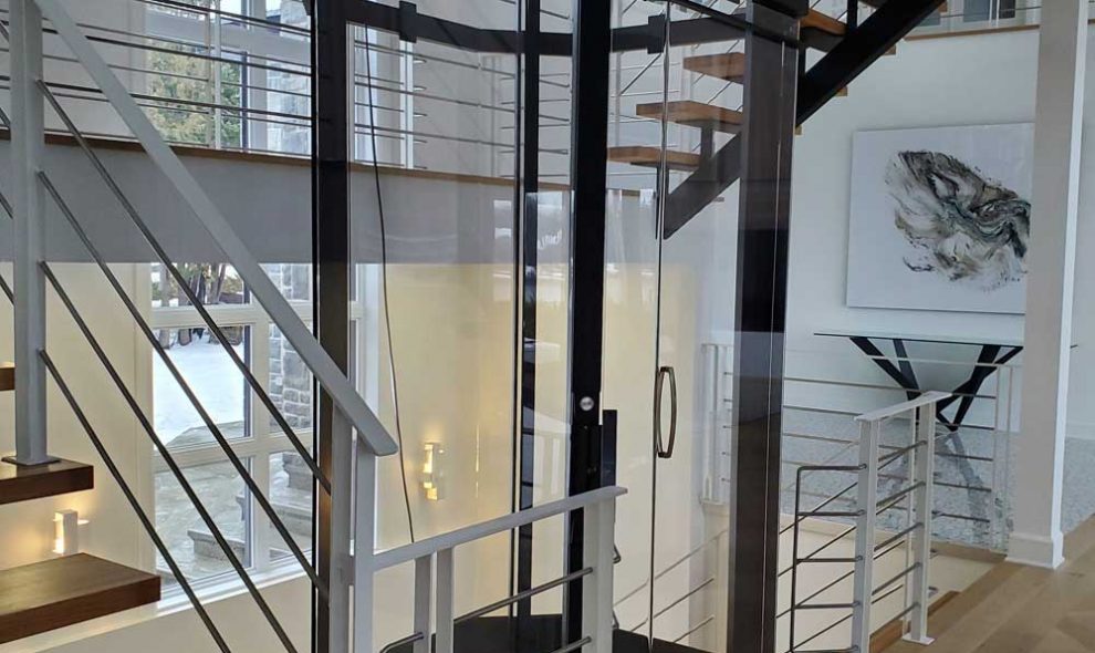 Octagonal glass elevator with black trim in luxury home