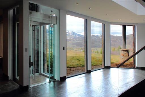 glass elevator next to a set of windows with scenic view.